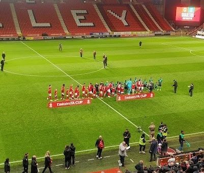 A photo of the two teams shaking hands on the pitch before the match.