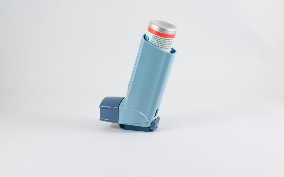 A blue inhaler set against a plain grey background.