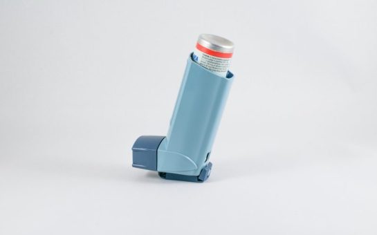 A blue inhaler set against a plain grey background.