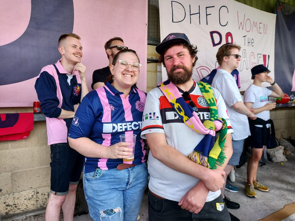 Two smiling Dulwich Hamlet Women fans standing on the terrace