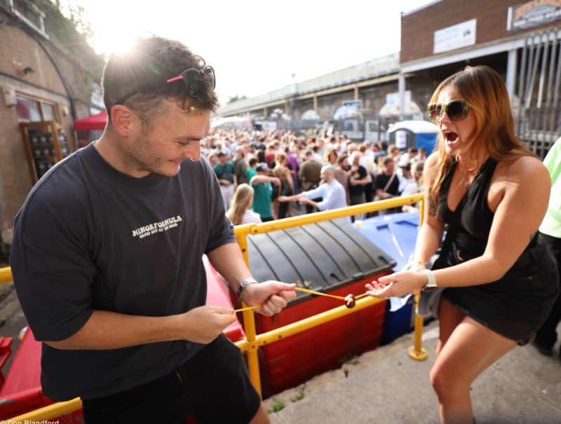 Image shows two people playing conkers with a big crowd in the background.