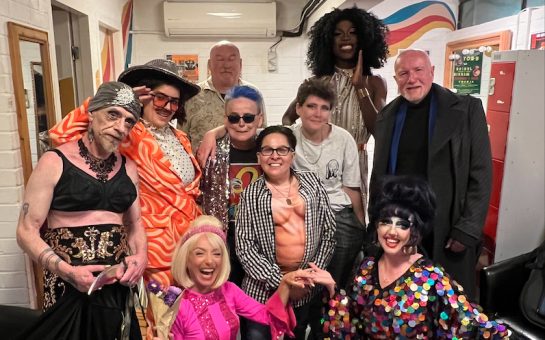 A landscape group photo capturing the performers of Songbook in their various costumes. They are smiling at the camera.