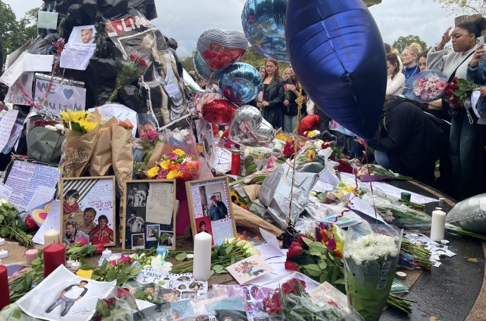 One Direction fans stood around the Peter Pan statue in Kensington Gardens, which is covered with flowers, letters and balloons