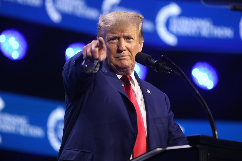 Donald Trump stood at a podium pointing at the camera