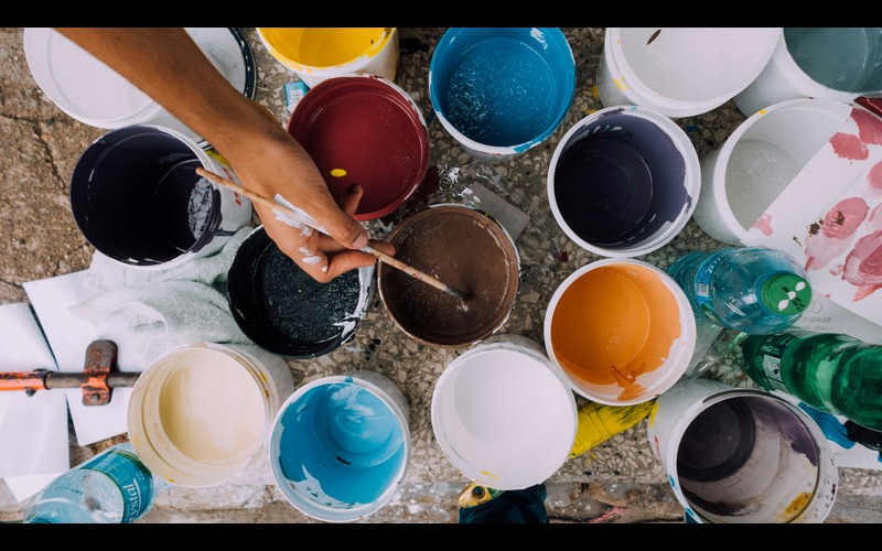 Picture of paint pots with hand holding paintbrush